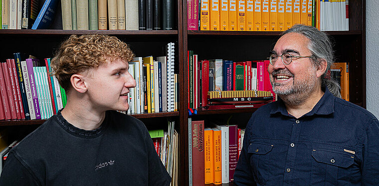 Moritz Kracht und Oliver Rosteck vor einem Bücherregal.